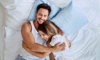 Happy couple lying on the bed hugging and smiling