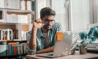 Man wearing glasses doing research on his laptop