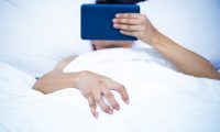 Man lying on the bed getting an urge to masturbate while holding his phone