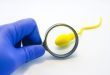 Doctor inspecting illustrated sperm with a magnifying glass